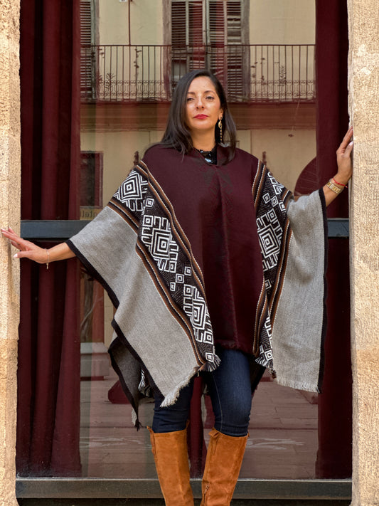 Woman wearing a patterned shawl over a plain garment, standing indoors.